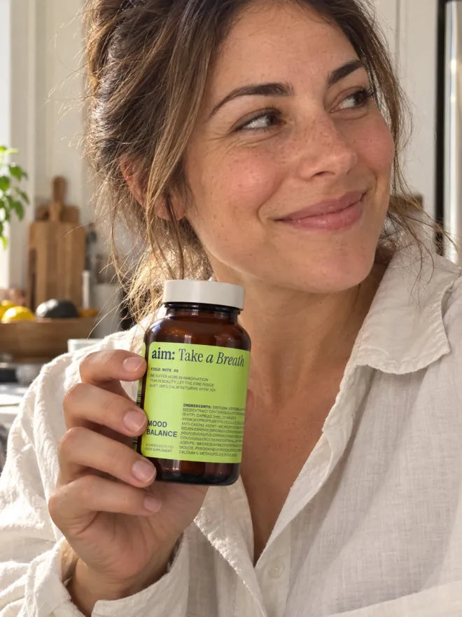 Someone in a kitchen holding a bottle of AIM Mood Balance