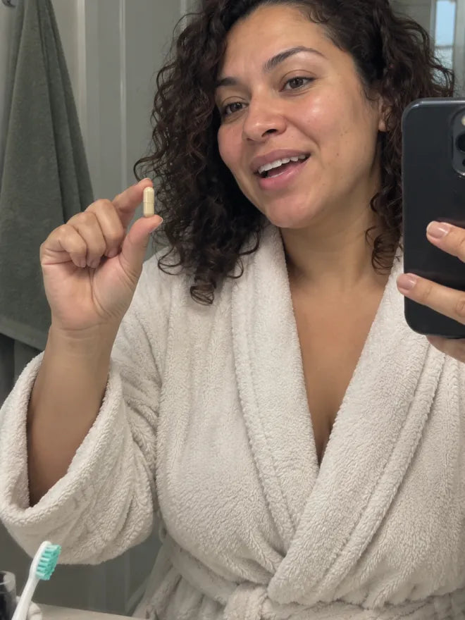 Someone in a bathrobe holding an AIM capsule before bed