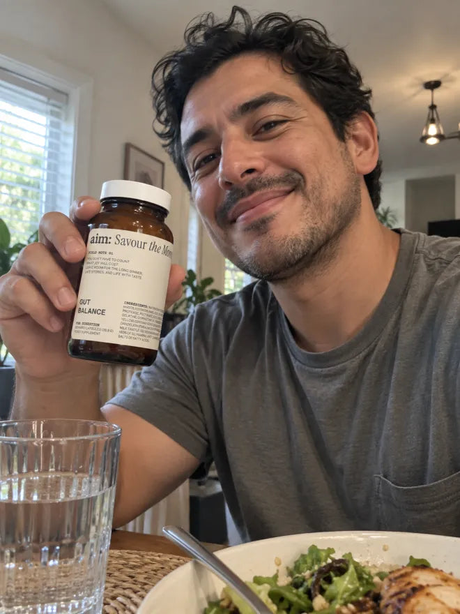 A man at a table with a meal, holding a bottle of AIM Gut Balance